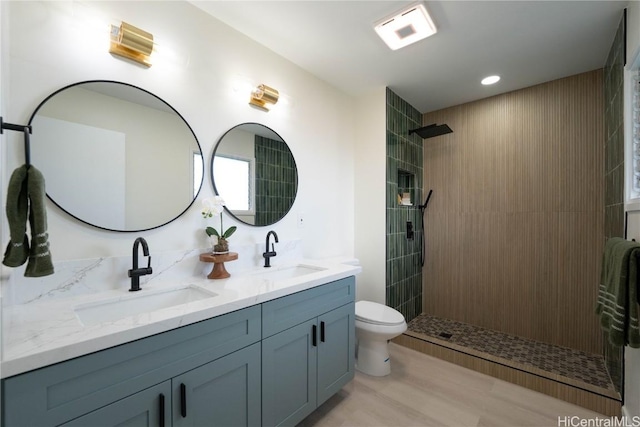 bathroom featuring hardwood / wood-style flooring, vanity, toilet, and a tile shower