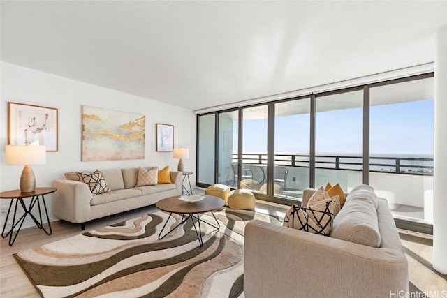 living room featuring light hardwood / wood-style flooring, expansive windows, and a water view