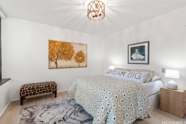 bedroom with light hardwood / wood-style flooring and a chandelier