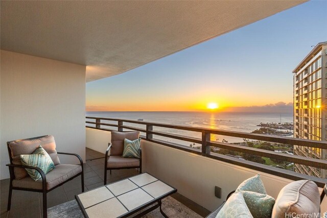 balcony at dusk with a beach view and a water view