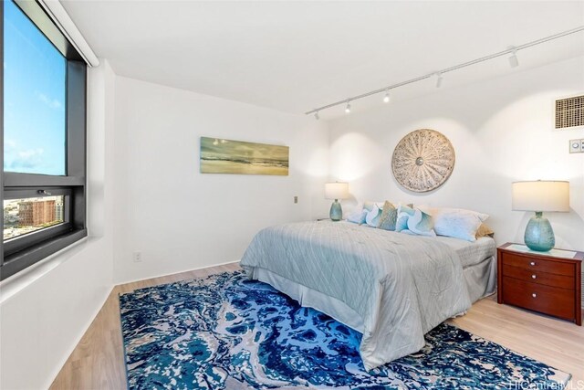 bedroom with rail lighting and light hardwood / wood-style flooring