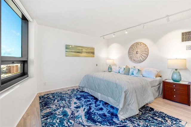 bedroom featuring track lighting and light hardwood / wood-style flooring