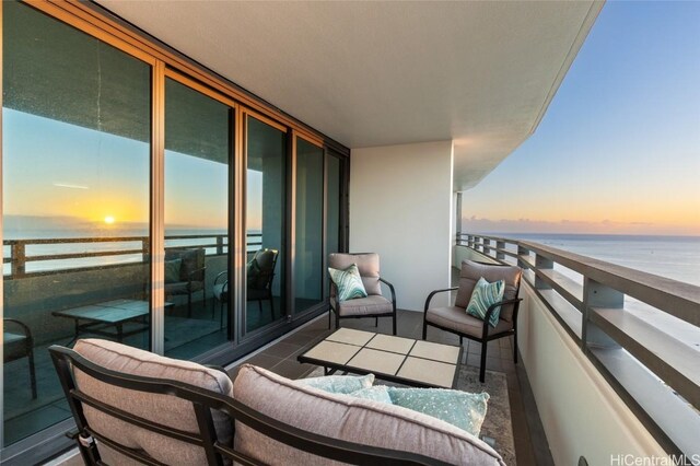 balcony at dusk featuring a water view