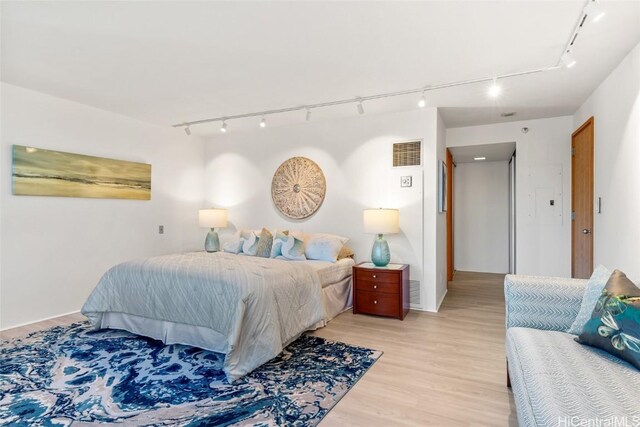 bedroom with rail lighting and light hardwood / wood-style floors