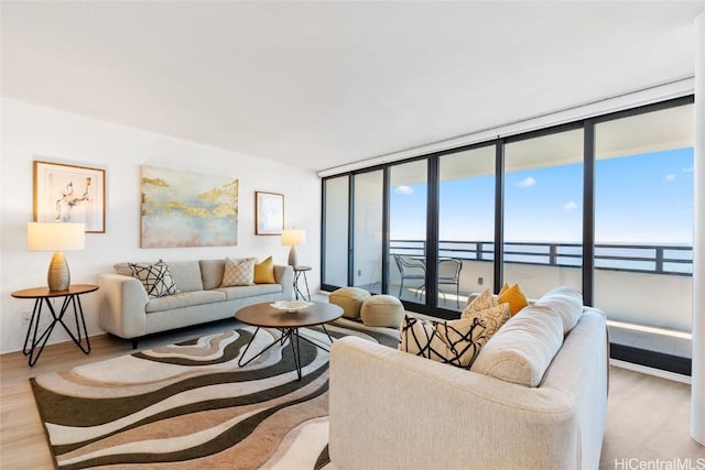 living room with wood-type flooring, a water view, and floor to ceiling windows