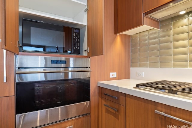 kitchen featuring stainless steel oven, black microwave, and backsplash