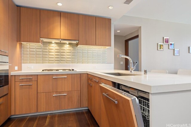 kitchen with dark wood-type flooring, sink, gas cooktop, kitchen peninsula, and decorative backsplash