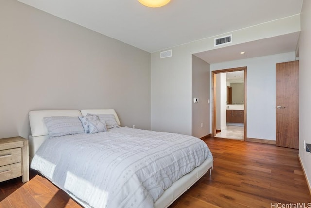 bedroom featuring connected bathroom and dark wood-type flooring