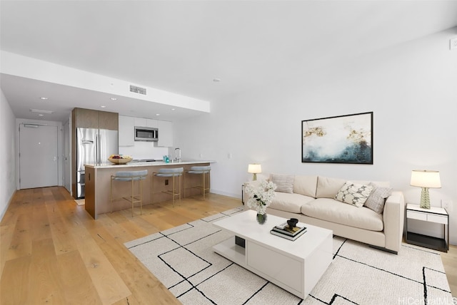 living room with light hardwood / wood-style floors and sink