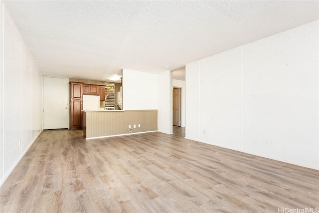 unfurnished living room with a textured ceiling and light hardwood / wood-style flooring