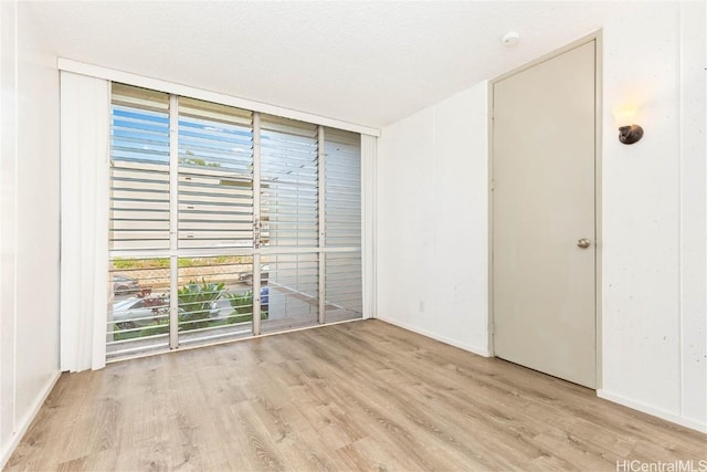 unfurnished room with expansive windows and light hardwood / wood-style floors