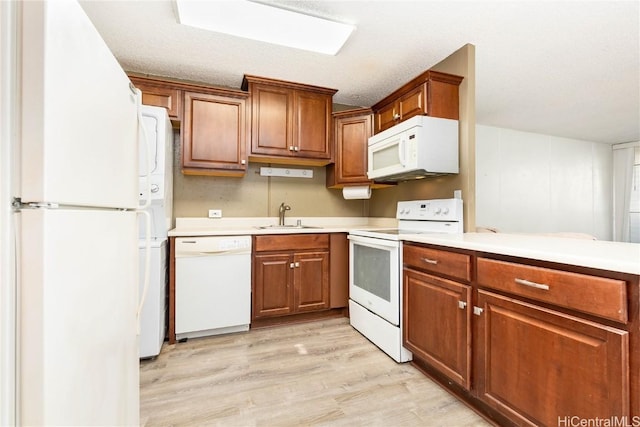 kitchen featuring a textured ceiling, white appliances, light hardwood / wood-style floors, and sink