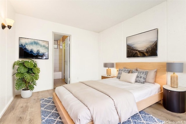 bedroom with ensuite bath and hardwood / wood-style floors