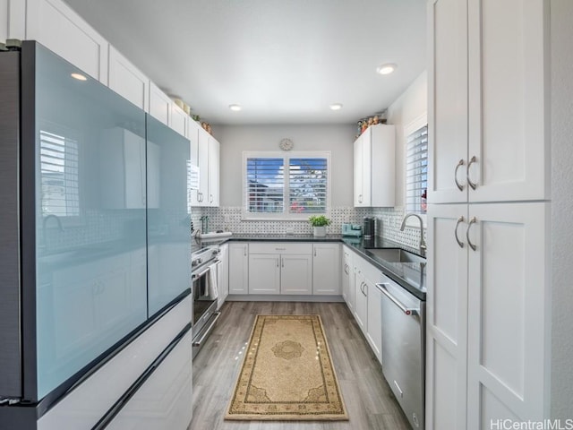 kitchen with appliances with stainless steel finishes, decorative backsplash, a sink, and white cabinets