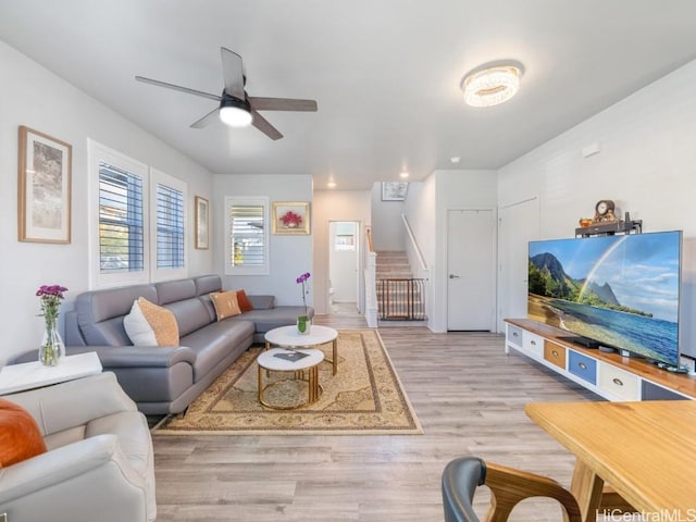 living area with ceiling fan, stairway, and wood finished floors