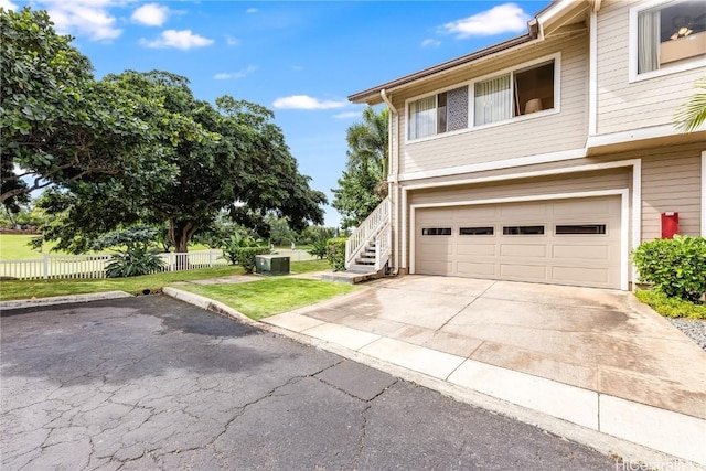 view of front of home with a garage, central air condition unit, and a front yard