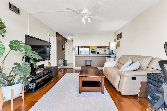 living room featuring a textured ceiling, ceiling fan, and wood-type flooring