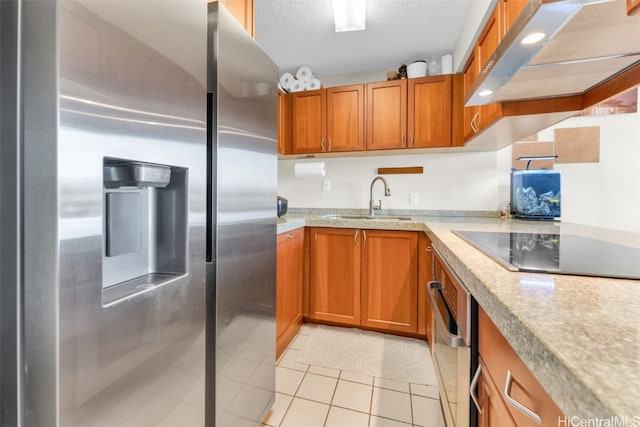 kitchen with stainless steel appliances, light tile patterned floors, a textured ceiling, sink, and exhaust hood