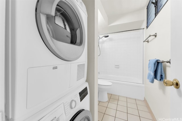 bathroom with toilet, tiled shower / bath combo, tile patterned floors, and stacked washer / dryer