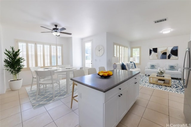 kitchen featuring ceiling fan, light tile patterned floors, plenty of natural light, a kitchen island, and white cabinetry