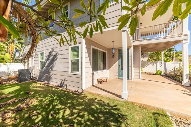 rear view of property with central AC unit, a balcony, a yard, and a patio