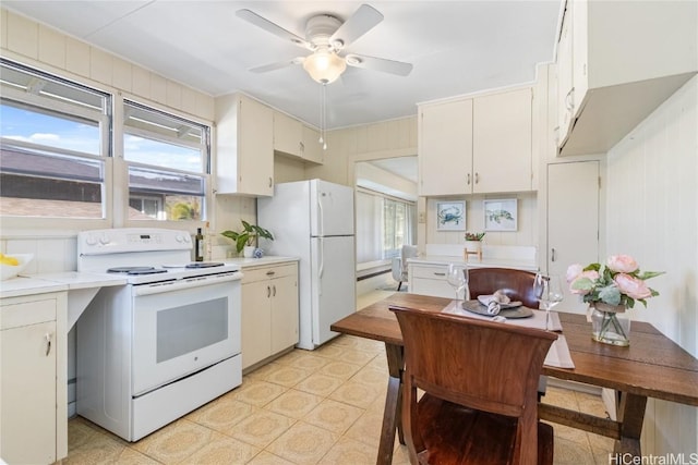 kitchen with wooden walls, white cabinetry, white appliances, ceiling fan, and baseboard heating