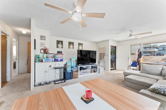 living room with a textured ceiling, ceiling fan, and light carpet