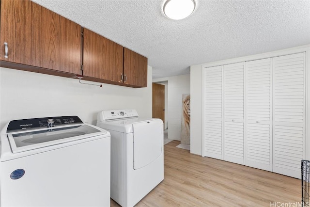 laundry area featuring cabinets, independent washer and dryer, a textured ceiling, and light hardwood / wood-style flooring