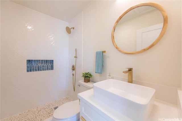 bathroom featuring tiled shower, toilet, and sink