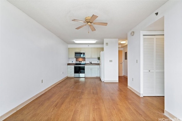 kitchen featuring light hardwood / wood-style flooring, ceiling fan, cream cabinetry, a textured ceiling, and stainless steel appliances