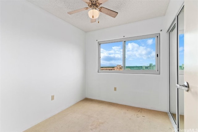 spare room featuring ceiling fan, light colored carpet, and a textured ceiling