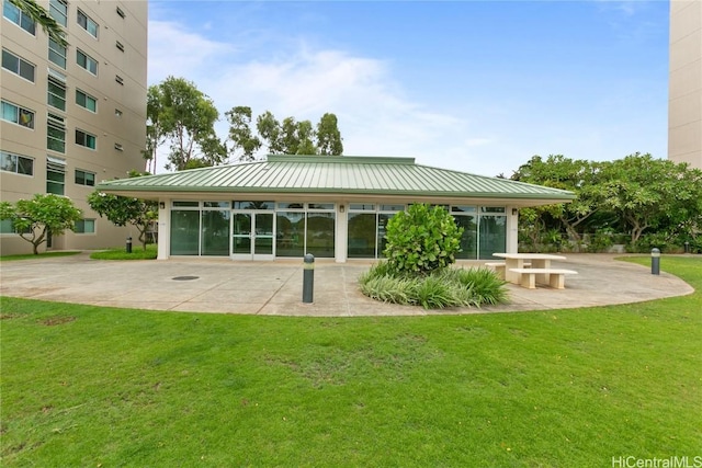 rear view of property with a standing seam roof, a patio area, a lawn, and metal roof