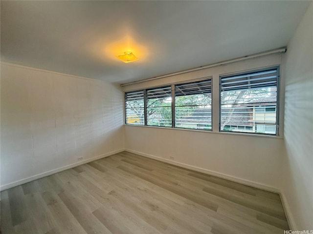 spare room featuring baseboards and light wood finished floors