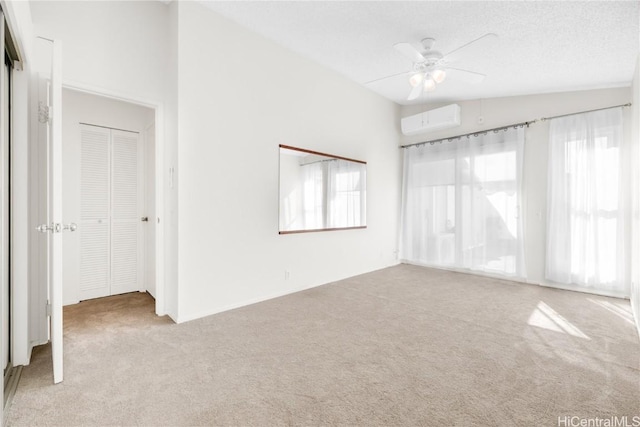 empty room featuring ceiling fan, light colored carpet, lofted ceiling, and a wall mounted AC