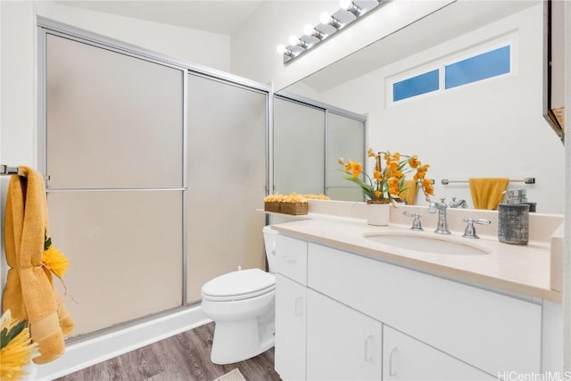 bathroom featuring hardwood / wood-style flooring, vanity, toilet, and a shower with door