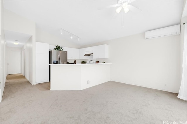 unfurnished living room with light colored carpet, track lighting, a wall mounted AC, and ceiling fan