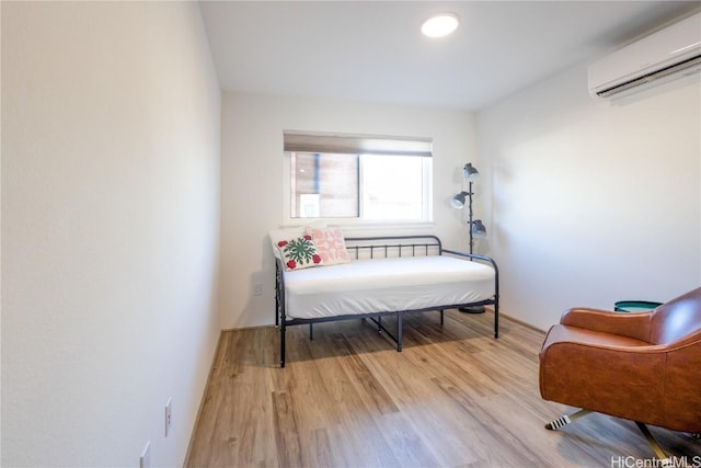 sitting room featuring a wall mounted air conditioner and light hardwood / wood-style flooring