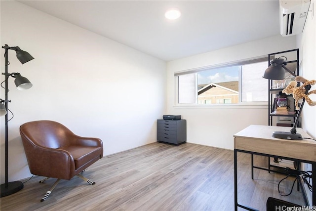 office with a wall mounted AC and light hardwood / wood-style flooring