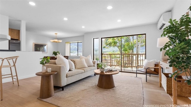 living room featuring light hardwood / wood-style floors, a wall mounted AC, and a notable chandelier