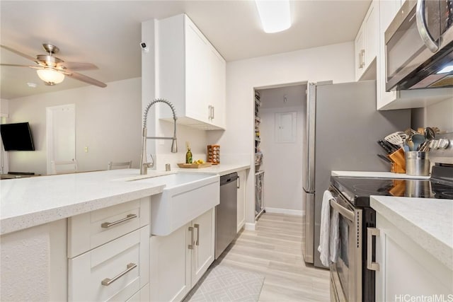 kitchen featuring white cabinets, ceiling fan, light stone countertops, appliances with stainless steel finishes, and light hardwood / wood-style floors