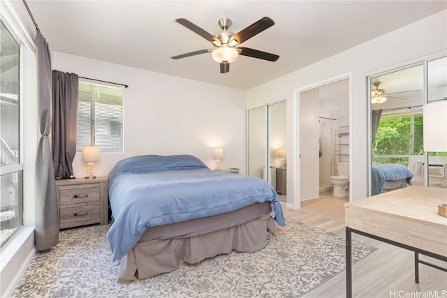 bedroom featuring multiple windows, ensuite bathroom, ceiling fan, and light wood-type flooring