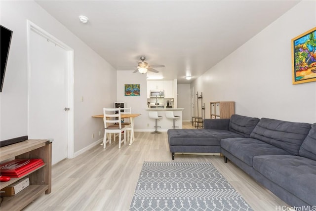 living room featuring ceiling fan and light hardwood / wood-style flooring