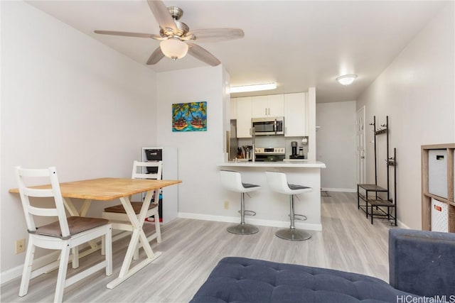 kitchen featuring white cabinets, stainless steel appliances, kitchen peninsula, and light hardwood / wood-style floors