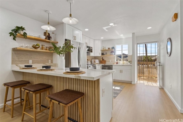 kitchen featuring white cabinets, a kitchen bar, kitchen peninsula, and hanging light fixtures