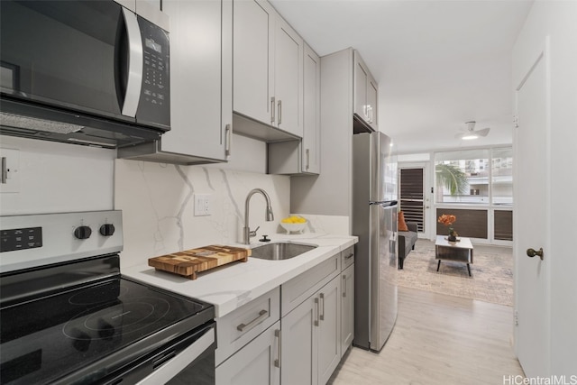 kitchen featuring stainless steel refrigerator, light stone countertops, sink, light hardwood / wood-style flooring, and electric stove