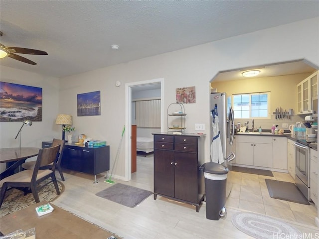 kitchen featuring dark brown cabinets, a textured ceiling, stainless steel appliances, ceiling fan, and white cabinets