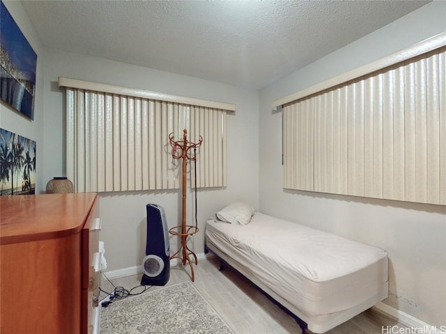 bedroom with a textured ceiling and light hardwood / wood-style flooring