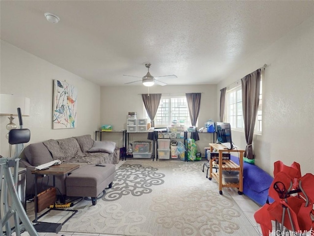 living room featuring light tile patterned floors, a textured ceiling, and ceiling fan