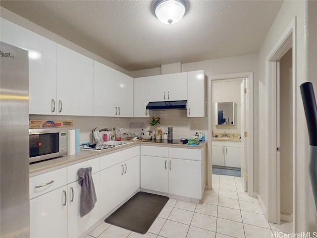 kitchen with appliances with stainless steel finishes, tasteful backsplash, a textured ceiling, white cabinets, and light tile patterned flooring