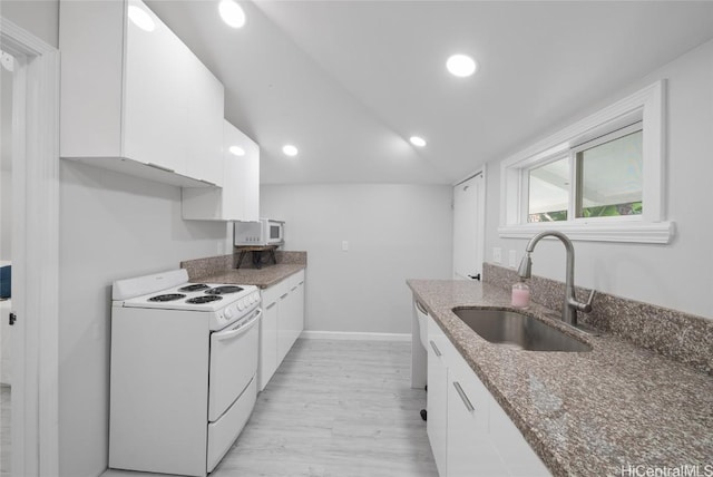 kitchen featuring dark stone counters, white appliances, sink, white cabinets, and light hardwood / wood-style floors